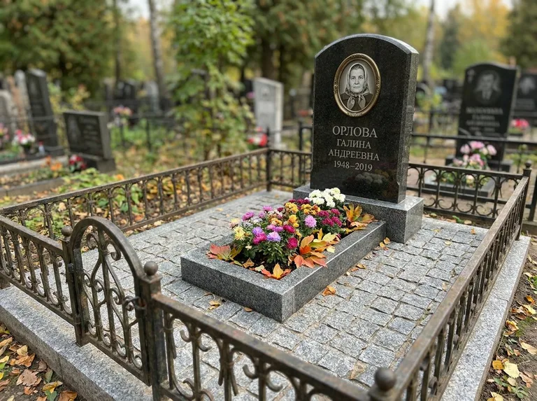 Благоустроенное захоронение с гранитной плиткой, оградой и цветником в Липецке
