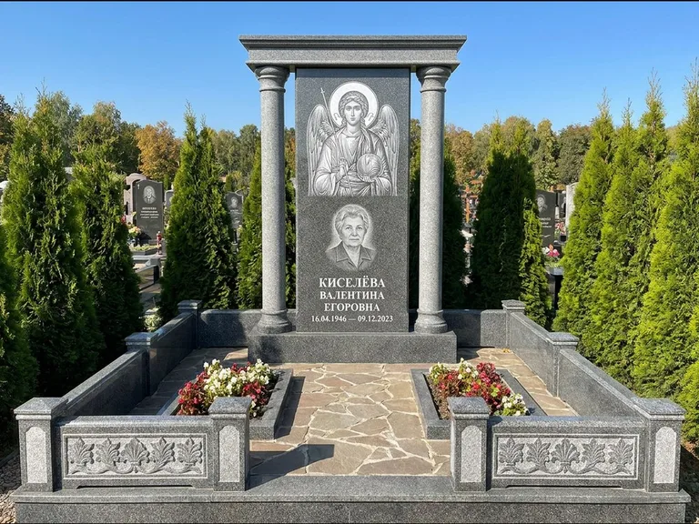 Памятник с гравировкой иконы: массивная стела с двускатным навершием-домиком — гравировка Николая Чудотворца, живая изгородь из туи, работа «Журавлёв» в Липецке