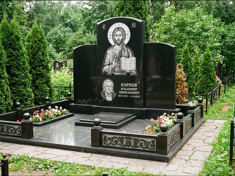 Памятник с гравировкой иконы: широкая панорамная стела с золочёным нимбом — гравировка образа Матроны Московской, цветник с белыми хризантемами, работа «Мельникова» в Липецке