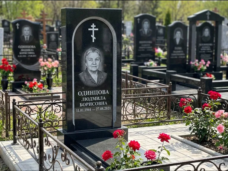 Памятник из чёрного гранита — скромная невысокая стела с крестом с терновым венцом, работа «Лаврентьева» в Липецке