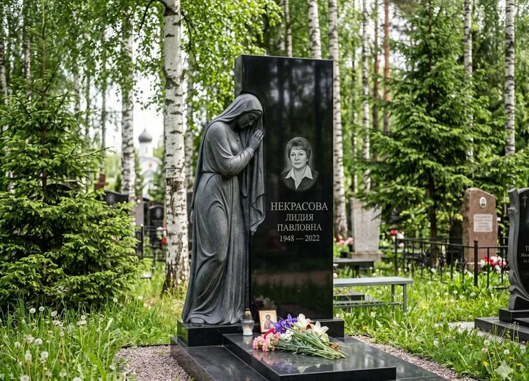 Гранитная фигура скорбящего мужчины у чёрной стелы в Липецке